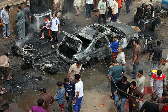 Baghdad bombings: People stand at the scene of one of the explosions