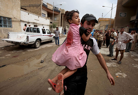 Baghdad bombings: A man carries an injured girl