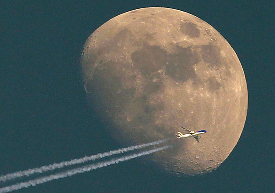 24 hours in pictures: A jet  flies past the waxing moon in Switzerland