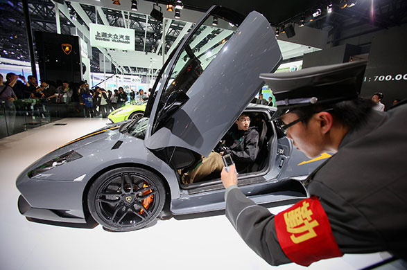 Beijing car show: Chinese security personnel takes pictures beside a Lamborghini Murciélago