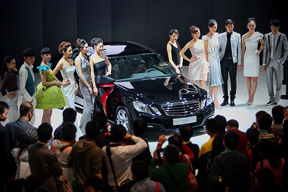 Beijing car show: Models stand beside the world premiere display of Mercedes-Benz E300 L car 