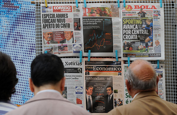 Week in Business: People read newspapers at a news stand in Lisbon, Portugal