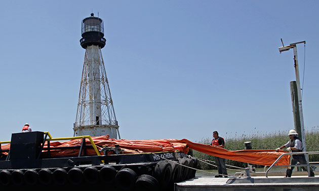 Deepwater oilrig: Workers move containment booms to a smaller vessel on the Mississippi River
