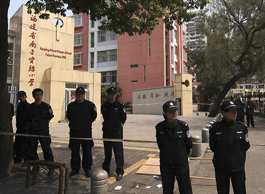 China school violence:  Policemen guard the entrance of a primary school in Nanping
