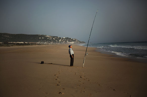 24 hours in pictures: Cadiz, Spain: A fisherman watches his rod as he is fishes on a beach 