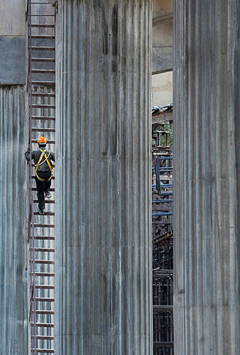 24 hours in pictures: Bangalore, India: An engineer uses a ladder to climb a pillar