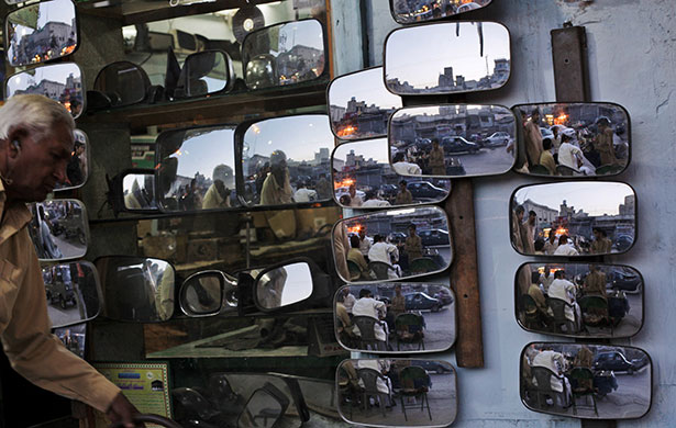 24 hours in pictures: Rawalpindi, Pakistan: A man looks at mirrors for sale at an auto shop