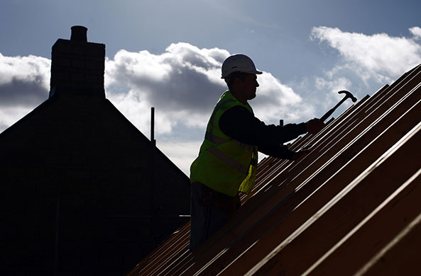 Week in Business: A builder works on the roof beams of a residential property in Swindon, UK