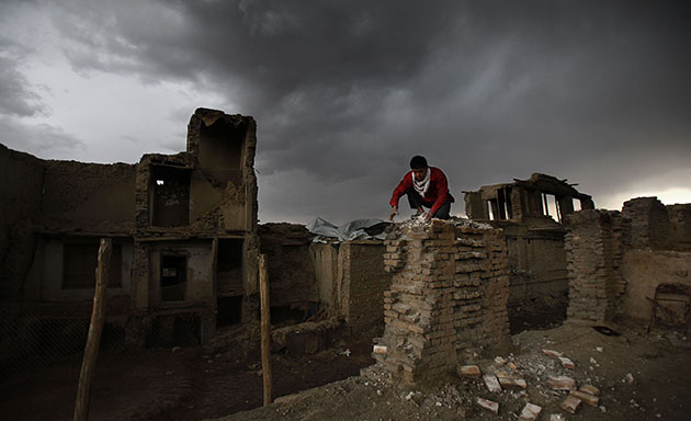 24 Hours in Pics: A boy removes brick from a wall of a building damaged in civil war in Kabul