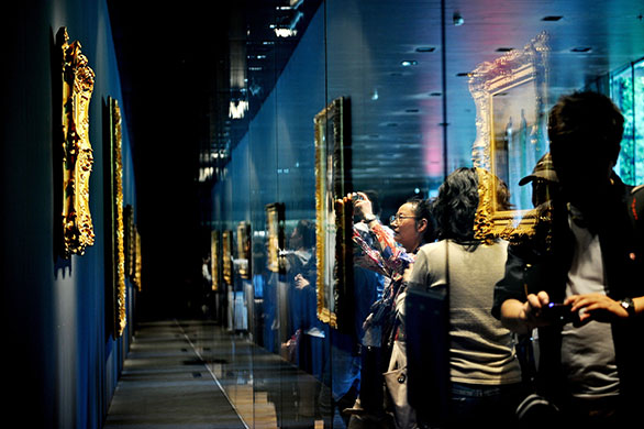 24 Hours in Pics: Visitors look at art from France's Musee D'Orsay at Shanghai World Expo 