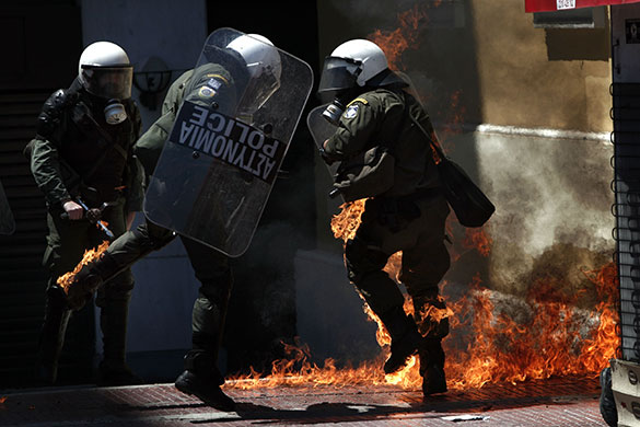 Athens Riot: A Greek riot policeman runs away from a fire in Athens