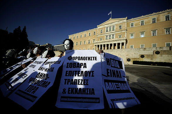 24 hours in pictures: Protestors wearing white masks sit outside Greek Parliament