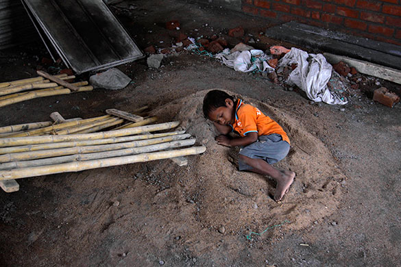 24 hours in pictures: An Indian boy sleeps as his parents work, in Hyderabad, India