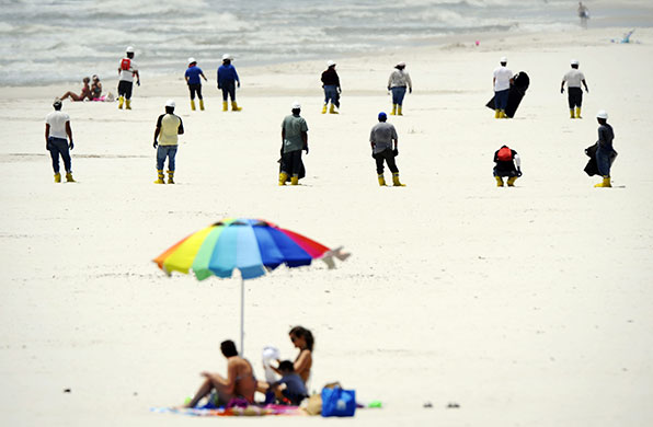 24 Hours in Pics: Workers walk the beach checking for any signs of oil in Alabama