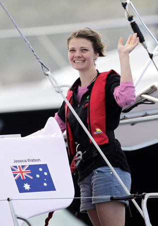 Jessica Watson waves as she sails past the finish line in Sydney Harbour