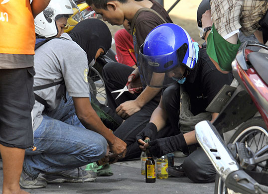 Bangkok Riots: Anti government red shirt protesters prepare bottles to use as petrol bombs