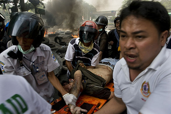 Bangkok Riots: Thai rescue personal carry a badly wounded man during clashes in Bangkok