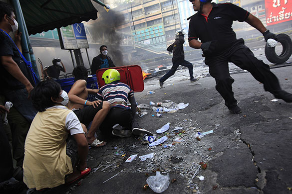 Bangkok Riots: Anti-government protesters cover as Thai soldiers fire shots in Bangkok