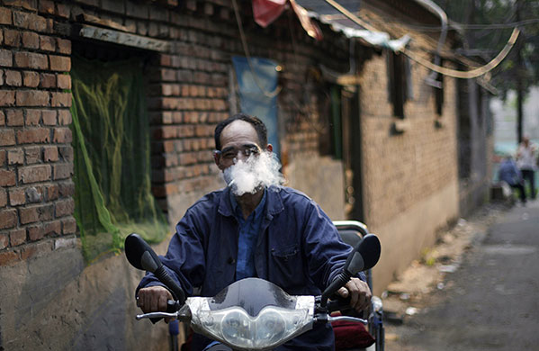 24 hours in pictures: Beijing, China: A Chinese man smokes a cigarette while riding his bike