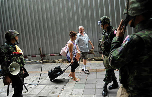 Thailand protests: A foreigner and his Thai companion walk by armed soldiers