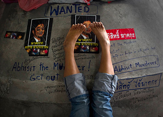 Thailand protests: Protestor rests her feet upon graffiti of Prime Minister Abhisit