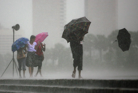 24 hours in pictures: Colombo, Sri Lanka: woman loses her umbrella in high winds and heavy rain 