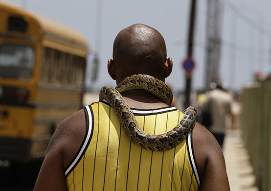 24 hours in pictures: A man carries his pet snake around his neck on a street in Havana