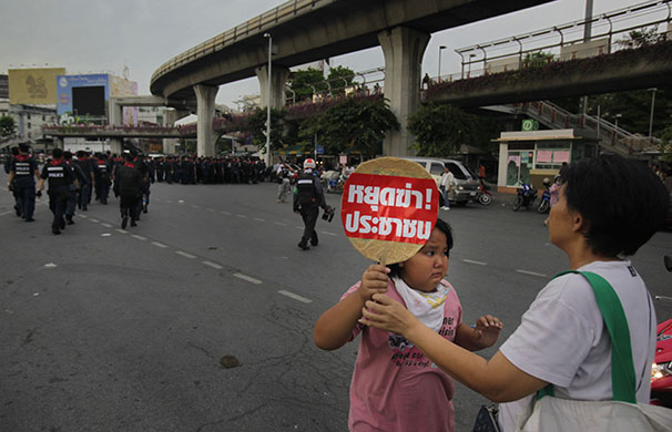 bangkok standoff: A girl carries a fan with the message  to stop killing people in Bangkok