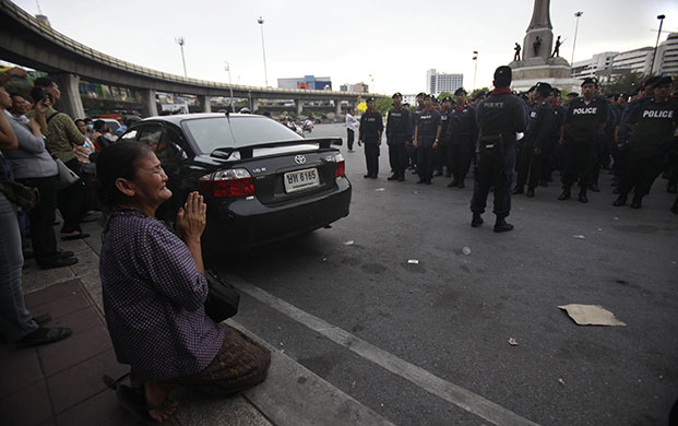 bangkok standoff: A woman prays as police get ready in Bangkok