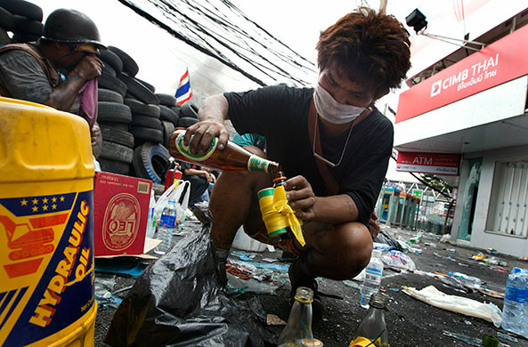 Thai clashes: A Thai anti-government  protester fills a bottle to make a gasoline bomb
