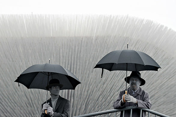24 hours in pictures: Performers painted in gray hold umbrella