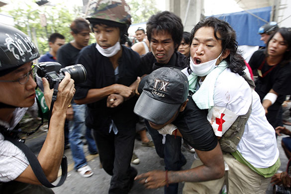 Bangkok protests: Anti government protesters evacuate an injured comrade during clashes