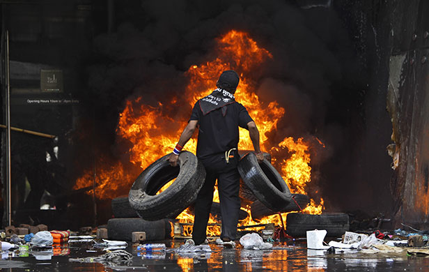 red shirt protesters: An anti-government protestor piles tires on a fire at a shopping centre