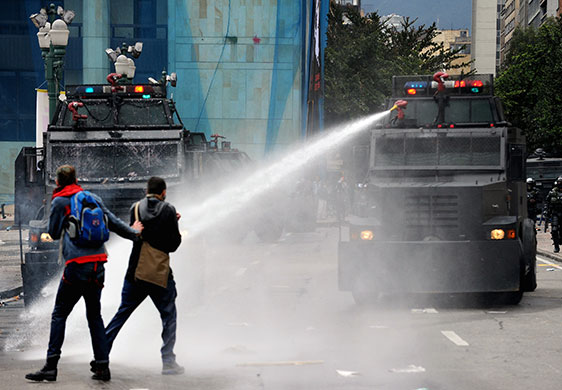 May Day protests: Bogota, Colombia: Riot police use a water cannon to disperse demonstrators