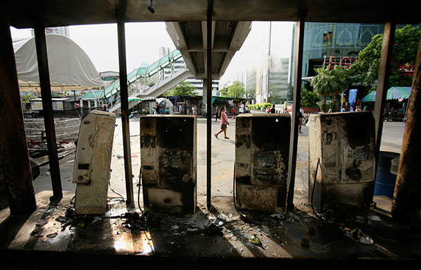 Thailand: A woman passes by a row of burned telephone booths 
