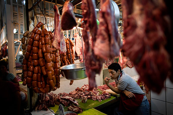24 hours in pictures: A man waits for customers in a butcher's shop, Guatemala