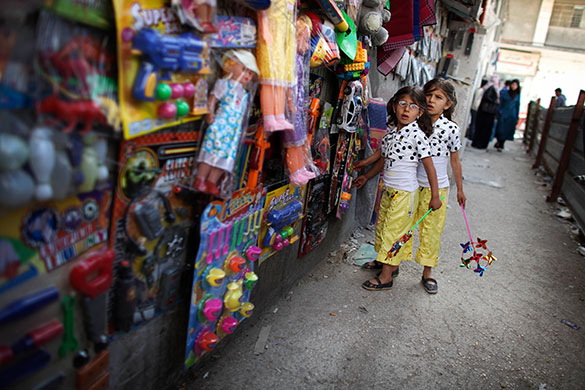 24 hours in pictures: Ramallah, Israel: Palestinian girls look at toys for sale, at a market