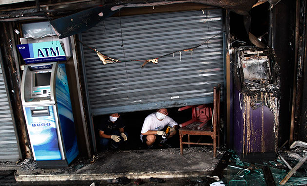 Thailand clean up: Masked shop owners peep through the partially opened shutter