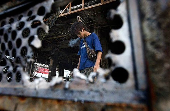 Thailand clean up: Thai residents check out damage to a burned out shop along Rama IV Road