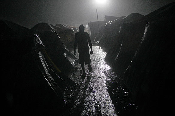24 Hours in Pics: A man walks under heavy rain at a camp in Port-au-Prince