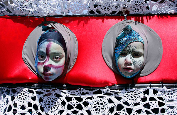 24hours: The heads of two children are seen through holes during Zinneke Parade