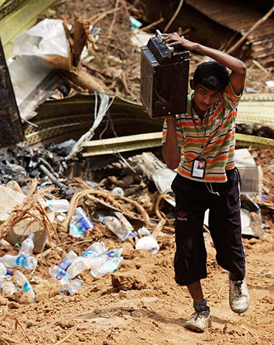 Air India crash 2: A worker carries an apparatus from the wreckage of a crashed Air India