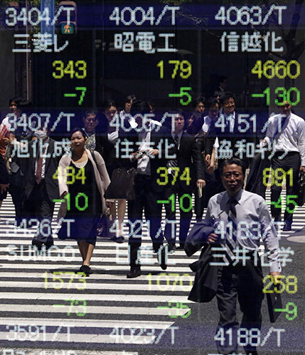 Week in Business: Pedestrians are reflected in a stock index board outside Tokyo brokerage