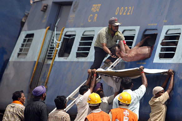 India train crash: Rescue workers take out the body of a dead passenger