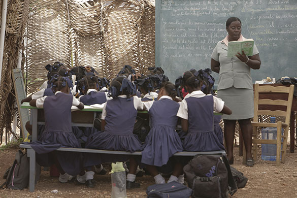 Haiti Schools Rebuild: A group of pupils writing, with teacher nearby