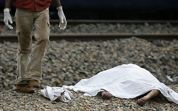 India train crash: A rescue worker stands next to a body of a passenger