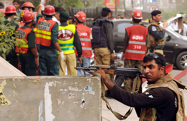 Lahore attack: A police officer takes up position as members of the rescue services