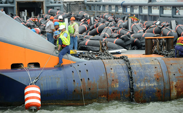 Deepwater Horizon oil rig: Oil spill : Men position a bouy on board a boat with
