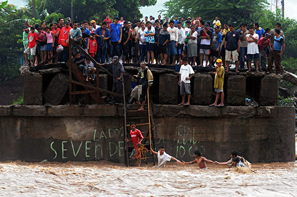 24 hours in pictures: La Libertad, El Salvador: People try to cross the overflowed Huiza river