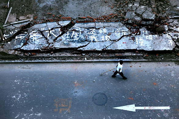 24 hours: Beijing, China: A worker walks past a demolished wal